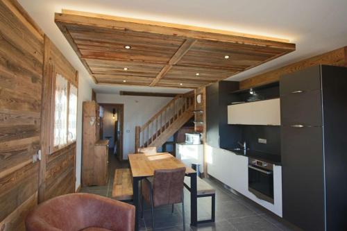 une cuisine avec une table et une cuisine avec un escalier dans l'établissement ODYSSEE B203 Vaste appartement en vieux bois sur les pistes, vue panoramique, à La Toussuire