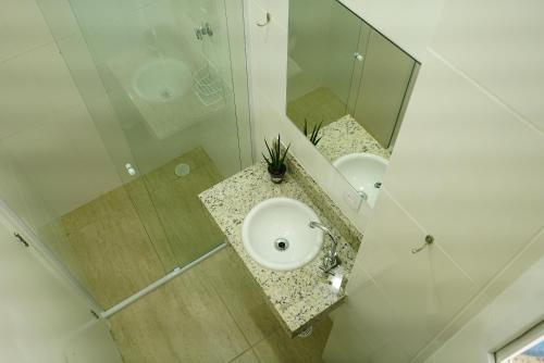 uma casa de banho com um lavatório e um espelho em Enseada Village Guarujá no Guarujá