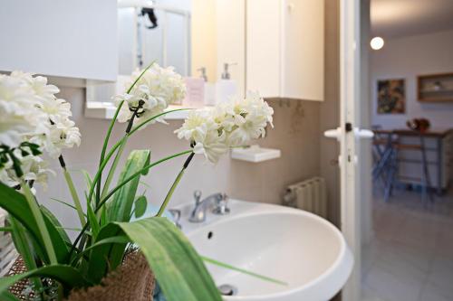 un bagno con lavandino e vaso con fiori bianchi di APARTMENT ORTENSIA - Regarda Travel a Lazise