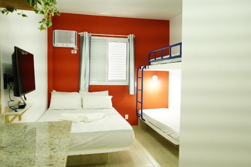 a small room with two bunk beds and a tv at Enseada Village Guarujá in Guarujá