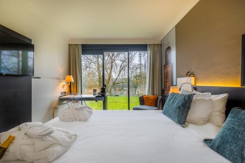 Schlafzimmer mit einem großen weißen Bett und einem Fenster in der Unterkunft Postillion Hotel Deventer in Deventer