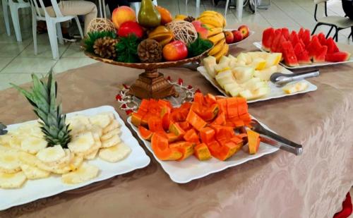 a table with three plates of fruit and a bowl of fruits at Biss Inn Hotel in Goiânia