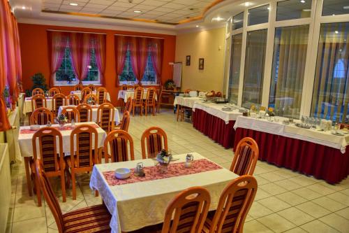 a dining room with tables and chairs and red walls at Hotel Penta Lux in Tata