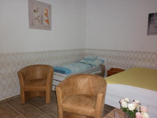 a room with a bed and two chairs and a table at Szép-Lak Makó in Makó