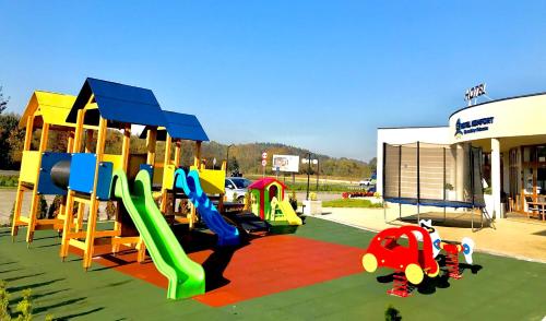 un parque infantil con toboganes y equipo de juegos frente a un edificio en Hotel Komfort, en Krzywaczka