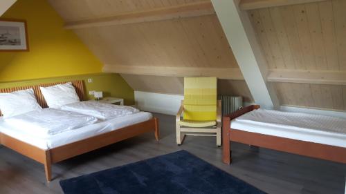 Habitación con 2 camas y silla amarilla en B&B de Oude Hofstee, en Maasdam