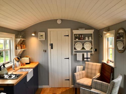 a kitchen with a white door and two chairs at Sheelin Shepherds Hut in Cavan