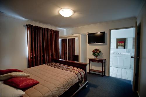 a bedroom with a bed and a television and a bathroom at Centrepoint Motor Inn in Rockhampton