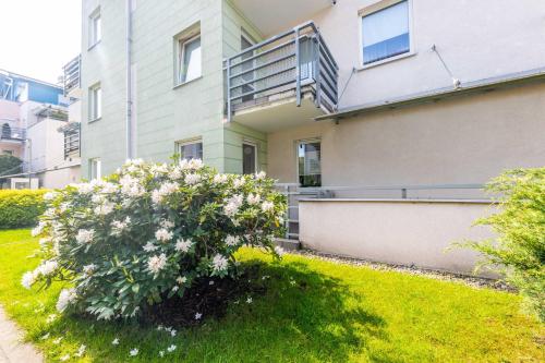 une maison avec une brousse fleurie devant elle dans l'établissement Victus Apartamenty, Apartament Liczi, à Sopot