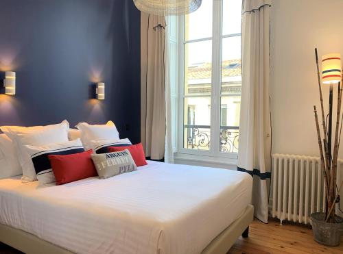 a bedroom with a large white bed with red pillows at Maison Manège Bordeaux Centre in Bordeaux