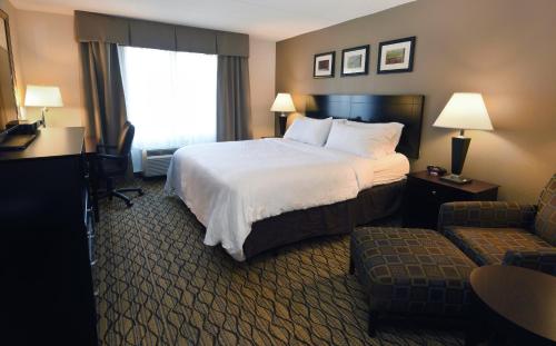 a hotel room with a large bed and a chair at Holiday Inn Express Milford by IHG in Milford