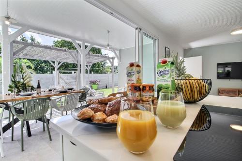 a table with a plate of food and two glasses of orange juice at Villa Zanzibar - 4 chambers, piscine privée, plage à pied, idéale pour découvrir le nord Caraibe in Case-Pilote