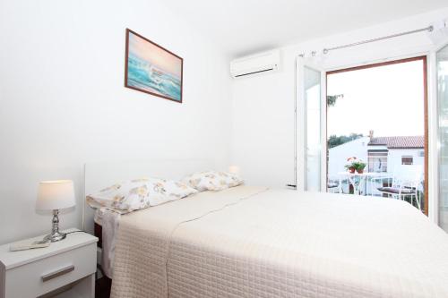 biała sypialnia z łóżkiem i oknem w obiekcie Apartment Gabriel w Rovinj