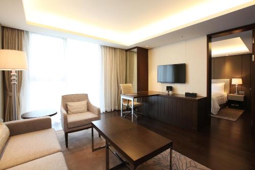 a living room with a room with a bed and a television at LOTTE City Hotel Daejeon in Daejeon