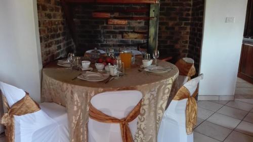 a table with white chairs and a table cloth at Hamba Kancane Ma-Africa Guest House in Graskop