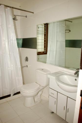 a white bathroom with a toilet and a sink at East End Retreat in New Delhi