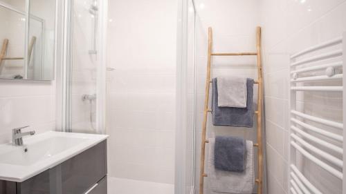 une salle de bain blanche avec un lavabo et un miroir dans l'établissement Danton Renaissance - F2 rénové - Tout équipé, au Havre