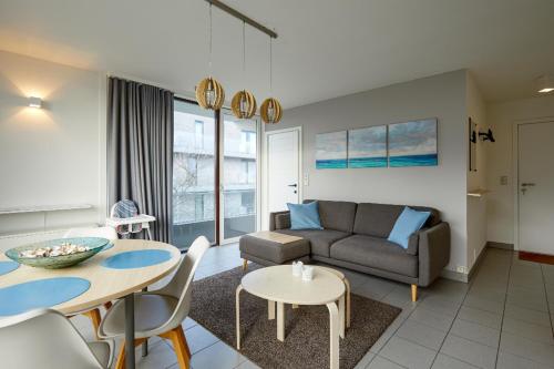 un soggiorno con un divano e un tavolo di Zeesymfonie Oostduinkerke a Koksijde