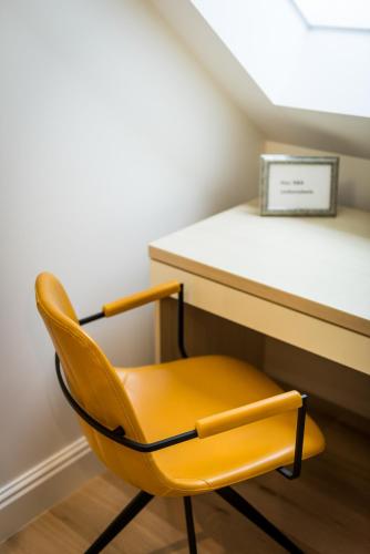 a yellow chair sitting in front of a desk at Een prachtige en luxueuze vakantiewoning dat is Hof Leskensdaele in Geraardsbergen
