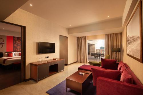 a hotel room with a red couch and a bed at Grand Mercure Bengaluru at Gopalan Mall - An Accor Brand in Bengaluru