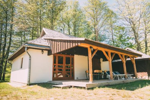 a small white cottage with a wooden roof at Viesu nams Melnsils in Melnsils