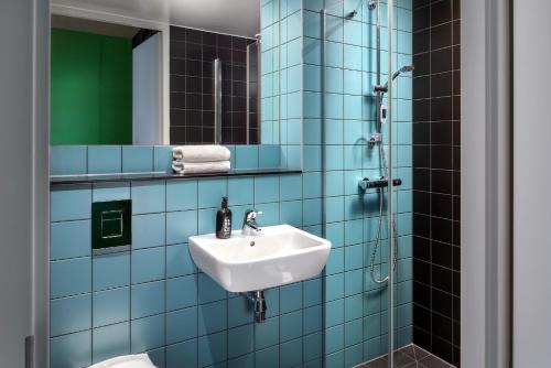 a bathroom with a shower, sink, and mirror at The Student Hotel Delft in Delft