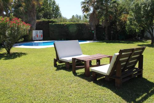 two chairs and a table and a bench in the grass at De Los Andes Hotel Boutique in Ciudad Lujan de Cuyo
