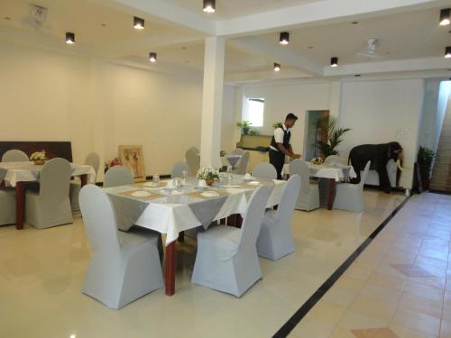 a man standing in a dining room with a table and chairs at Green Land Guest House in Pinnawala