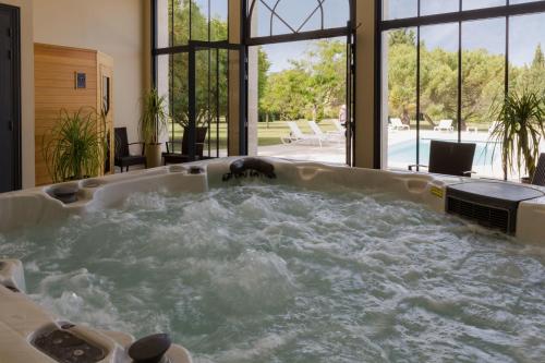 a jacuzzi tub in a room with windows at Le Logis du Péré in Saint-Coutant-le-Grand