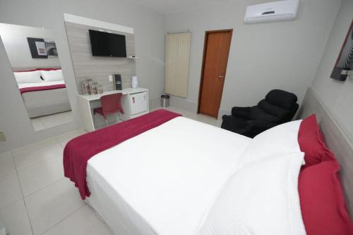 a hotel room with a white bed and a desk at Hotel Leon in Barbalha