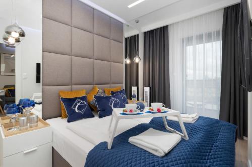 sypialnia z łóżkiem z niebieskimi poduszkami i stołem w obiekcie Apartamenty Gardenia Seaside by Noclegi Renters w Dziwnowie