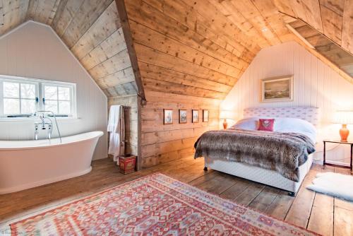 ein Schlafzimmer mit einem Bett und einer Badewanne im Dachgeschoss in der Unterkunft Bushes Oast by Bloom Stays in Sevenoaks