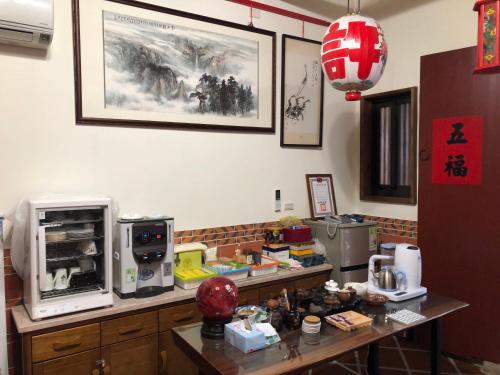 a kitchen with a microwave and a table with food at 金門后倉七號新古厝民宿 in Jinning
