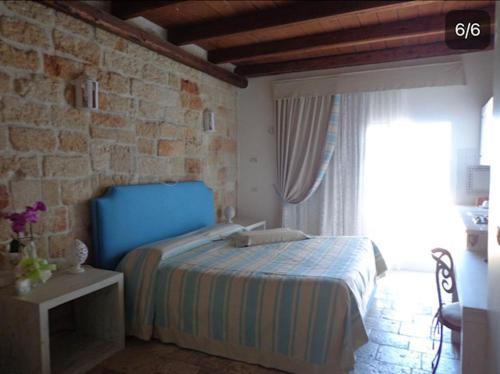 a bedroom with a blue bed and a stone wall at La Torretta del Senatore in Polignano a Mare