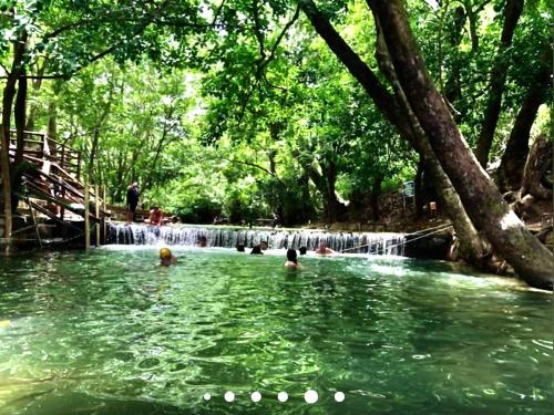a group of people swimming in a pond in front of a waterfall at Águas da Serra in Rio Quente