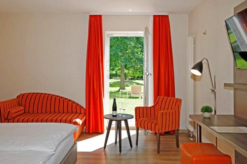 a bedroom with red curtains and a bed and a table at Landhotel Altes Wasserwerk GbR in Freinsheim