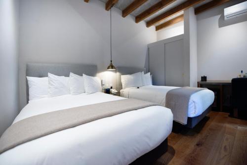 two beds in a hotel room with white sheets at Hotel Madi in San Miguel de Allende