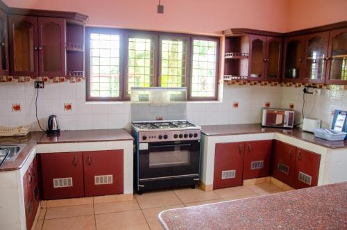 cocina con armarios rojos y fogones en Muralee's Riverside Villa in Kochi, en Kochi