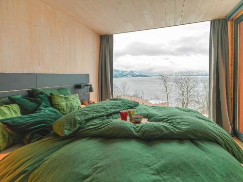 a bedroom with a large green bed with a large window at Funkis-cabin in Herand with fantastic fjordview in Samlanes