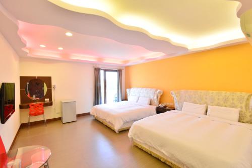 a hotel room with two beds and a tv at Kenting Coral Sea Resort Hotel in Kenting