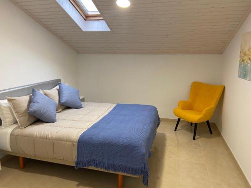 1 dormitorio con 1 cama y 1 silla amarilla en Os Arcos - Apartamentos Turísticos, en Portomarín