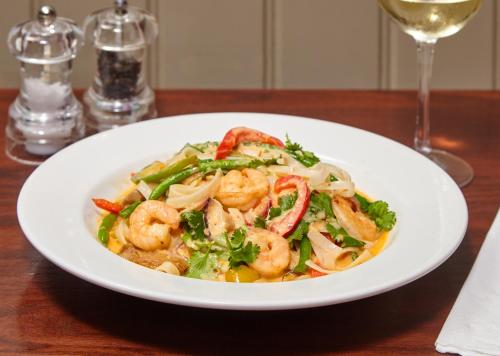 a white plate of shrimp pasta with a glass of wine at The Ormond At Tetbury in Tetbury