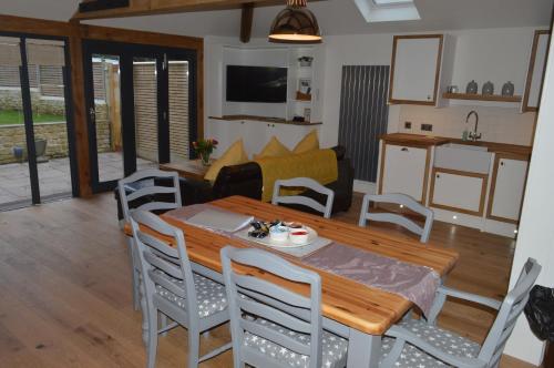 a kitchen and living room with a wooden table and chairs at Cedar Lodge 2 ensuite bedroom cottage near Bath in Box