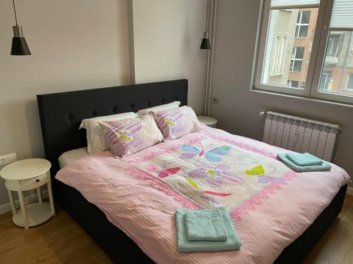 a bedroom with a large bed with a pink comforter at Solunska Stylish Apartment in Sofia