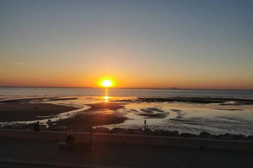 a sunset on the beach with the sun setting at Gite de la Digue in Wissant
