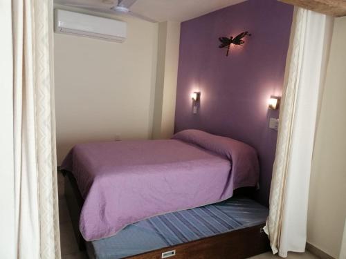 a bedroom with a purple bed with a butterfly on the wall at Aguacate Suites in Mazatlán