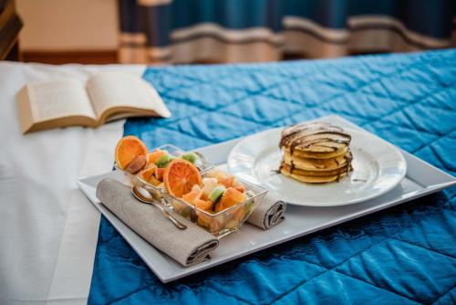 a plate of pancakes and fruit on a tray on a bed at Hotel Giulia in Lido di Camaiore