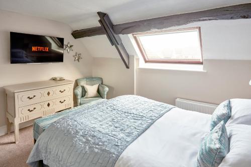 a bedroom with a bed and a tv and a chair at The Ormond At Tetbury in Tetbury