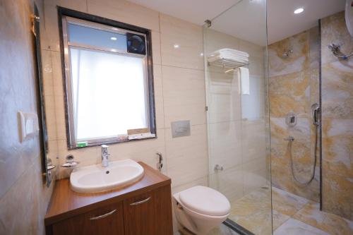een badkamer met een toilet, een wastafel en een douche bij The Avenue Hotel Ballygunge in Calcutta