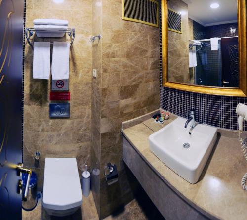 a bathroom with a sink and a toilet and a mirror at Kronos Hotel in Golbası